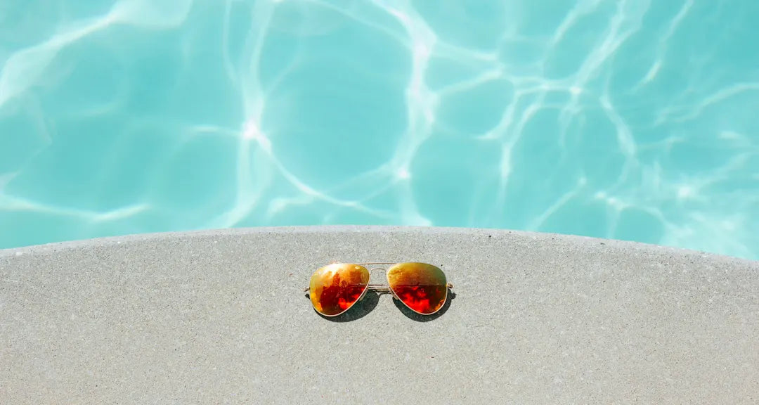 Eine Sonnenbrille am Poolrand als Sinnbild für das frische Tragegefühl der Manderwear Premium-Shorts aus Modal an heißen Sommertagen