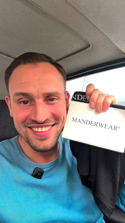 Ein Mann hält eine Verpackung einer Herrenunterhose in die Kamera